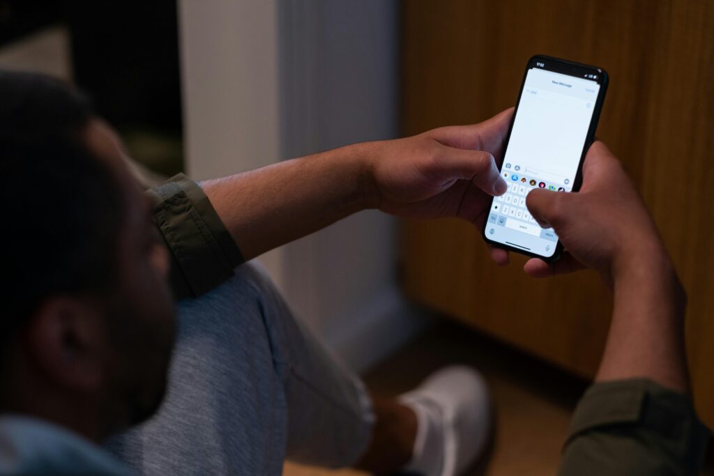 Close-up of a man texting on a smartphone indoors during evening time. Captures modern communication.
