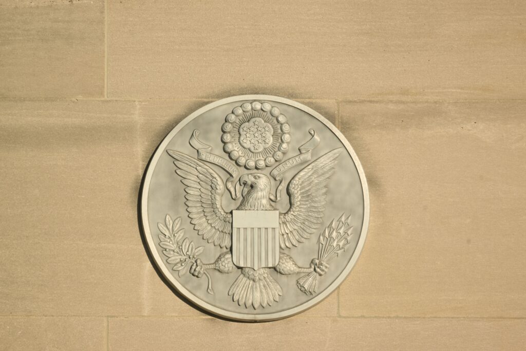 Stone carving of the Great Seal of the United States on a wall displaying an eagle with shield and olive branch.
