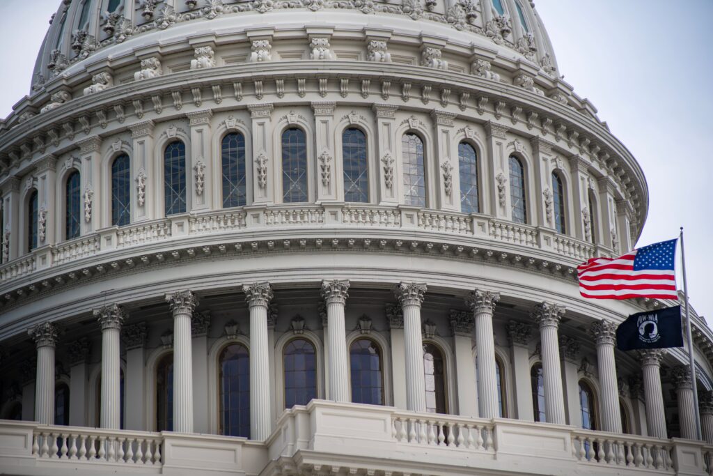 Detailed view of the US Capitol dome with the American flag flying nearby in Washington D.C.