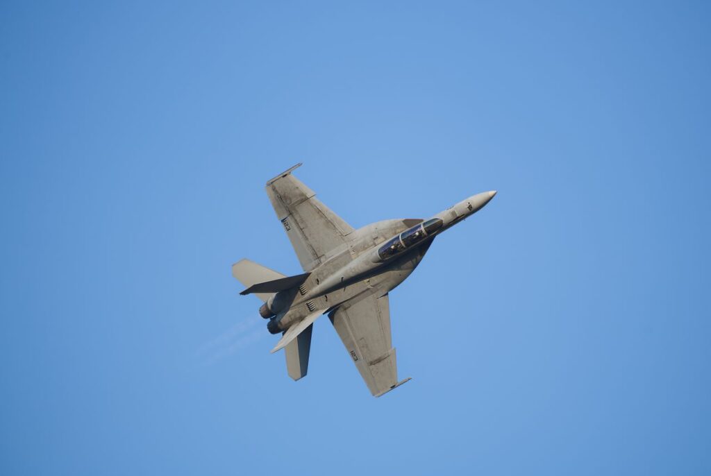 High-speed military jet soaring through the sky performing aerobatics.